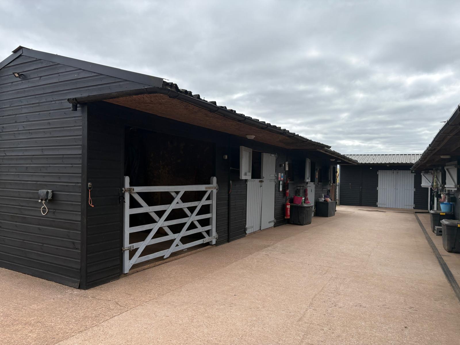 Black timber stable accommodation around the clean concrete yard