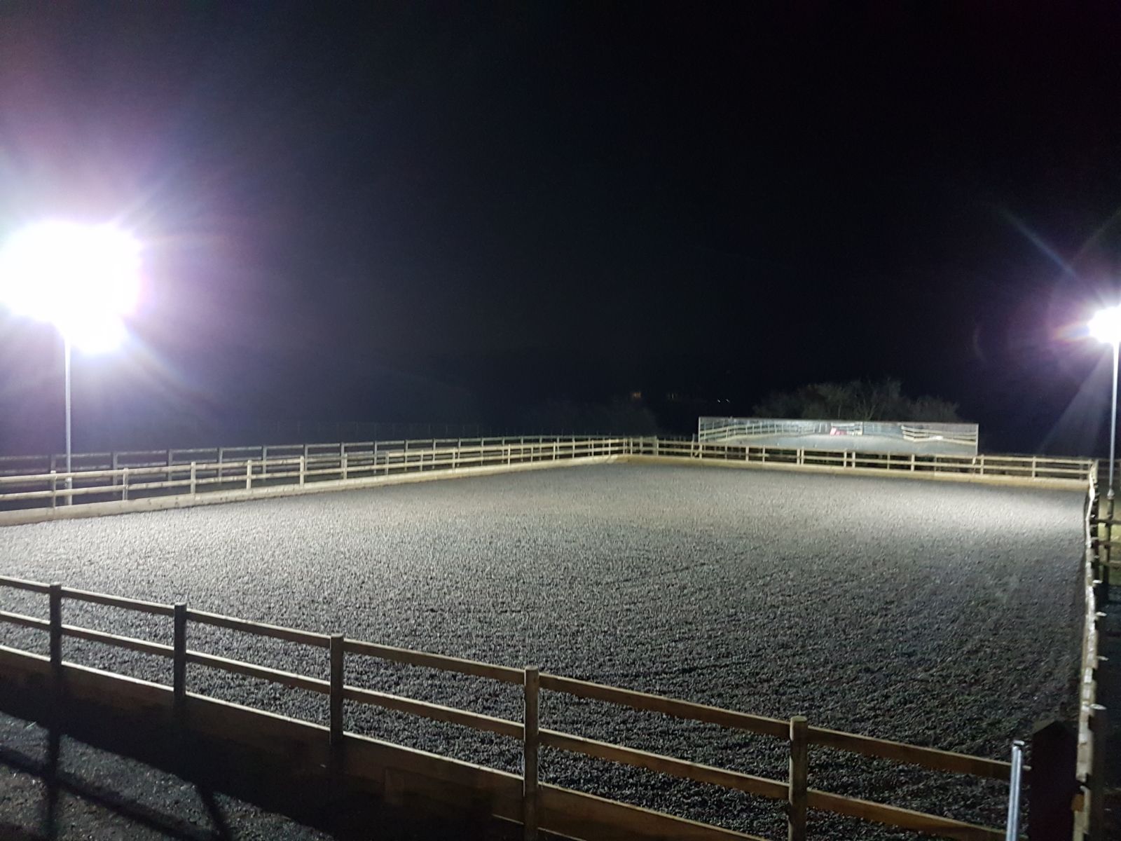 Floodlit all-weather arena at Middleton Livery Yard at night